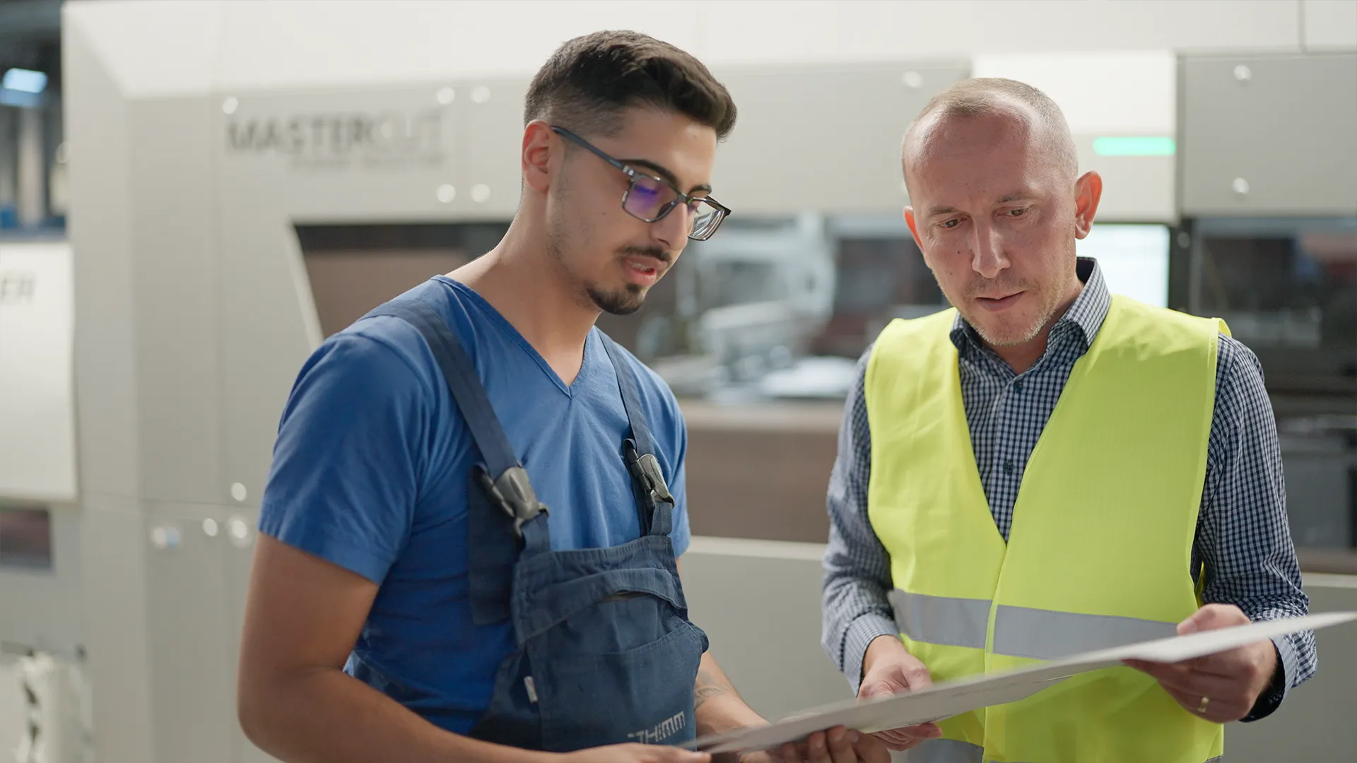 Operator and Plant Manager checking a die-cut sheet in front of the BOBST MASTERCUT