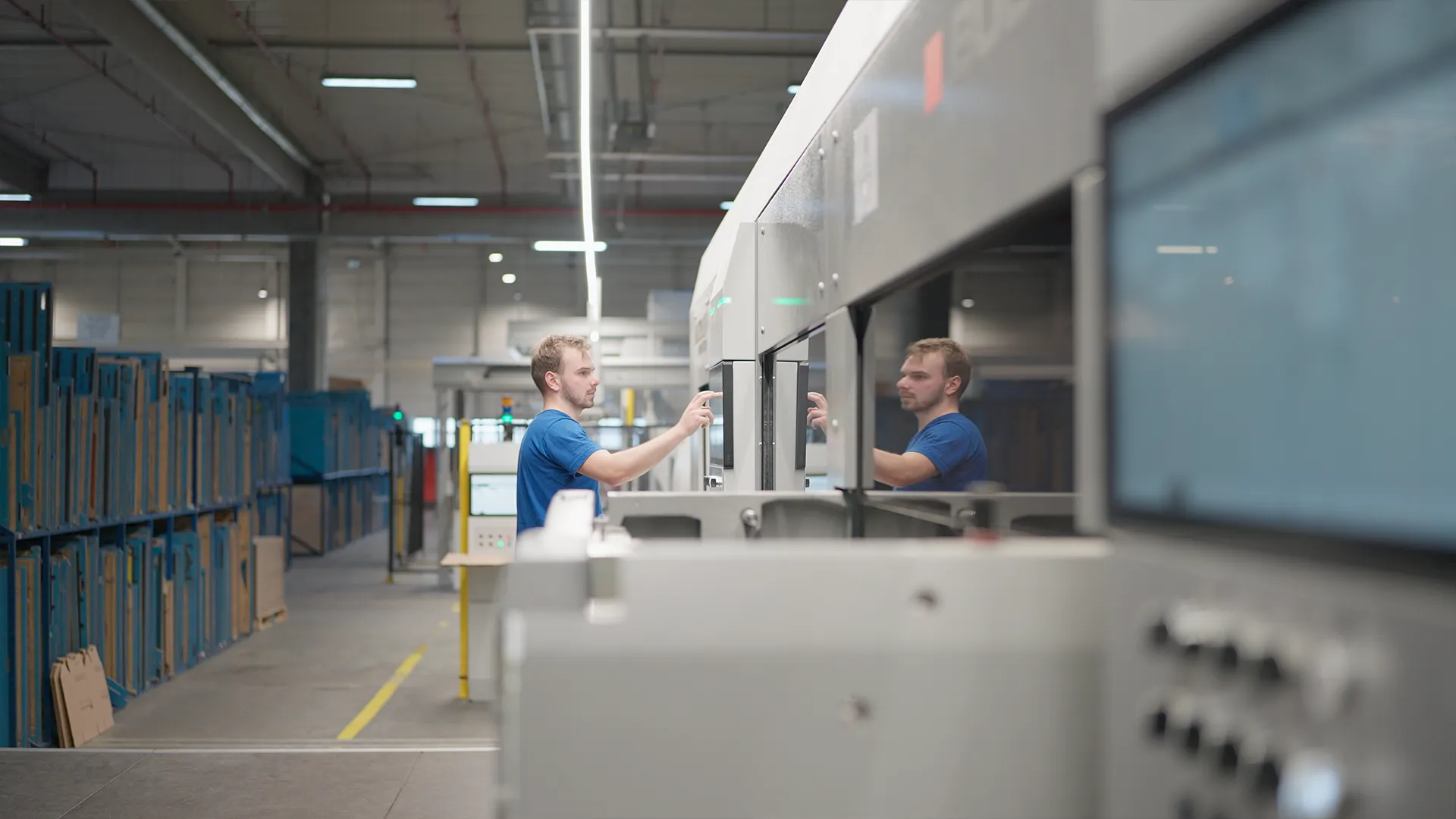 Operator setting up a job on the BOBST die-cutter touchscreen, reflected in the glass